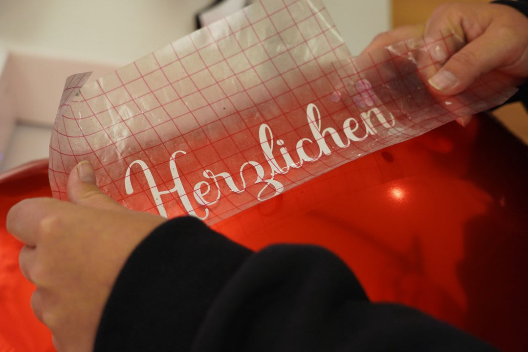 Ein geplotteter Text wird auf einen roten Herzballon geklebt.