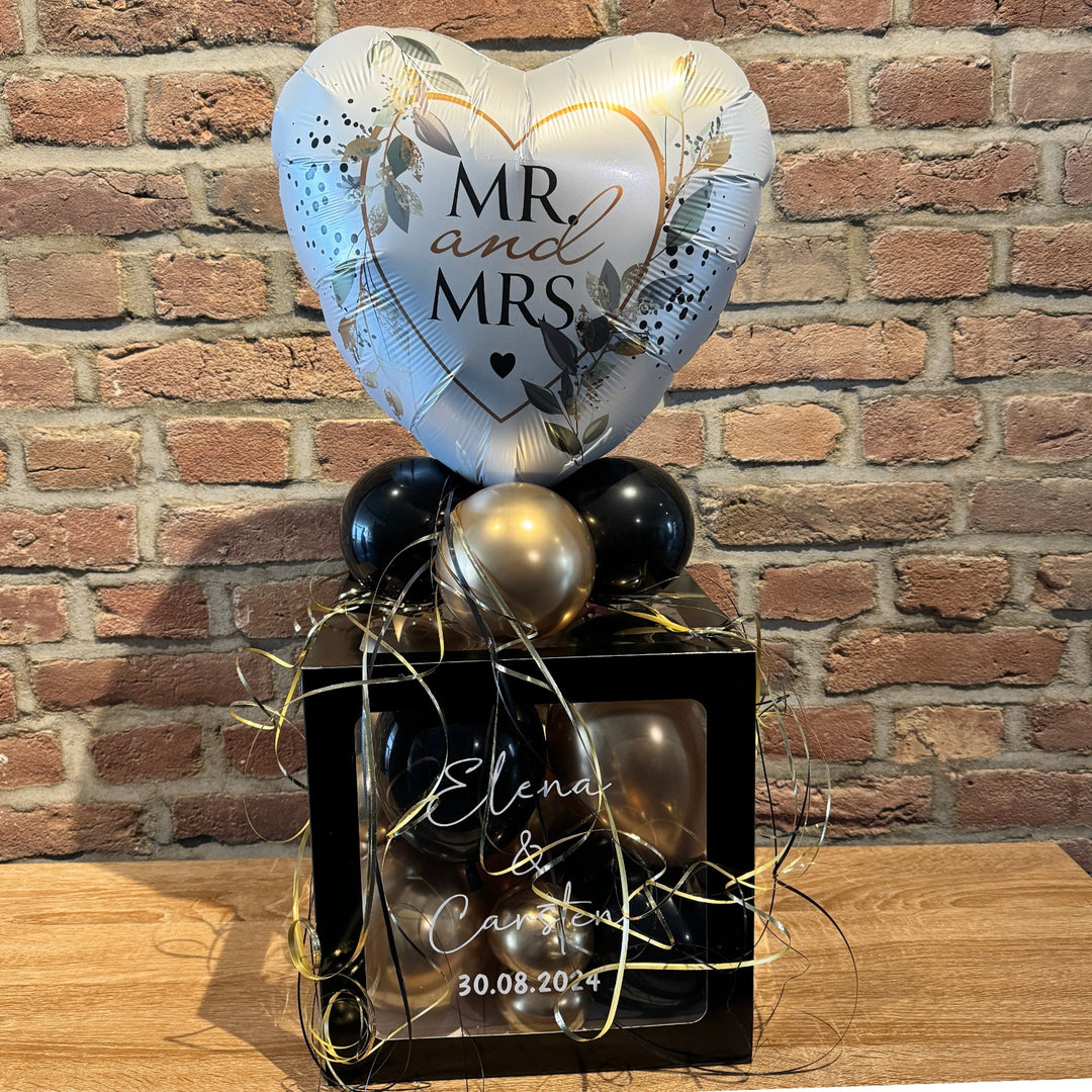 Herzballon "Mr and Mrs" mit personalisierter schwarzer Ballonbox, gefüllt mit goldenen und schwarzen Ballons – edles Hochzeitsgeschenk von HeyBalloon in Viersen