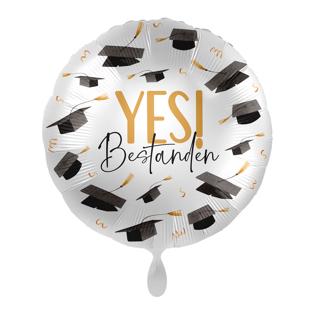 Runder Folienballon in Weiß mit gold-schwarzen Absolventenhüten und der Aufschrift „YES! Bestanden“
