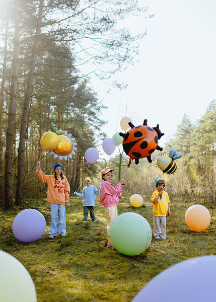 Kinder feiern draußen mit Folienballon Sonne und weiteren Natur-Ballons wie Marienkäfer und Biene