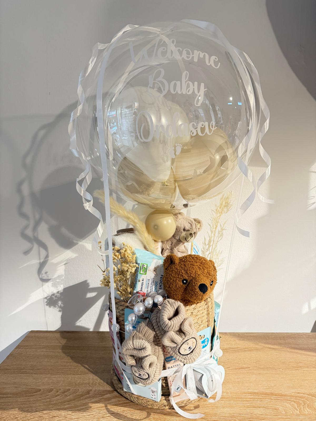 Transparenter Bubble-Ballon mit Welcome Baby Aufdruck als Geschenkbox mit Babyartikeln und Teddybär – liebevolle Geschenkidee zur Geburt