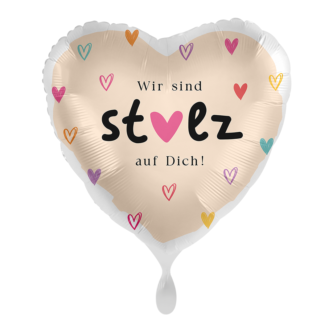 Herzförmiger Folienballon in Creme mit bunten kleinen Herzen und Schriftzug „Wir sind stolz auf Dich!“